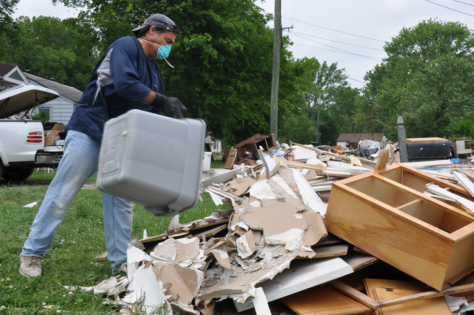 Volunteer worker carrying flood-damaged debris during home cleanup after a flood